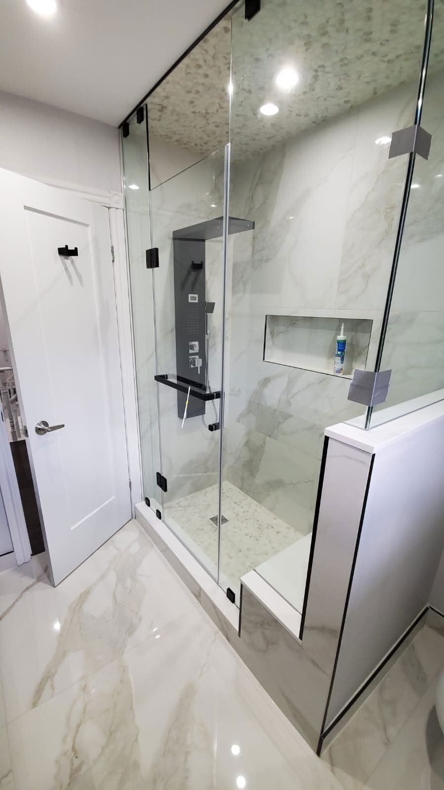 Frameless glass shower with black fixtures and marble tile in a GTA bathroom renovation